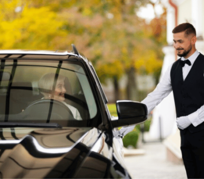 A valet or chauffeur opening a car door for a passenger