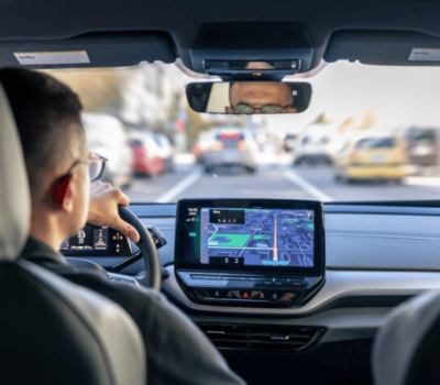 View from the back seat of a car, showing the driver and a GPS navigation screen