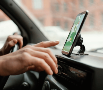 driver's hand touching a GPS navigation screen mounted on a car dashboard