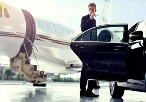 A man stands beside a sleek black car